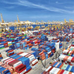 Container vessels near Jebel Ali Port with Dubai skyline in haze